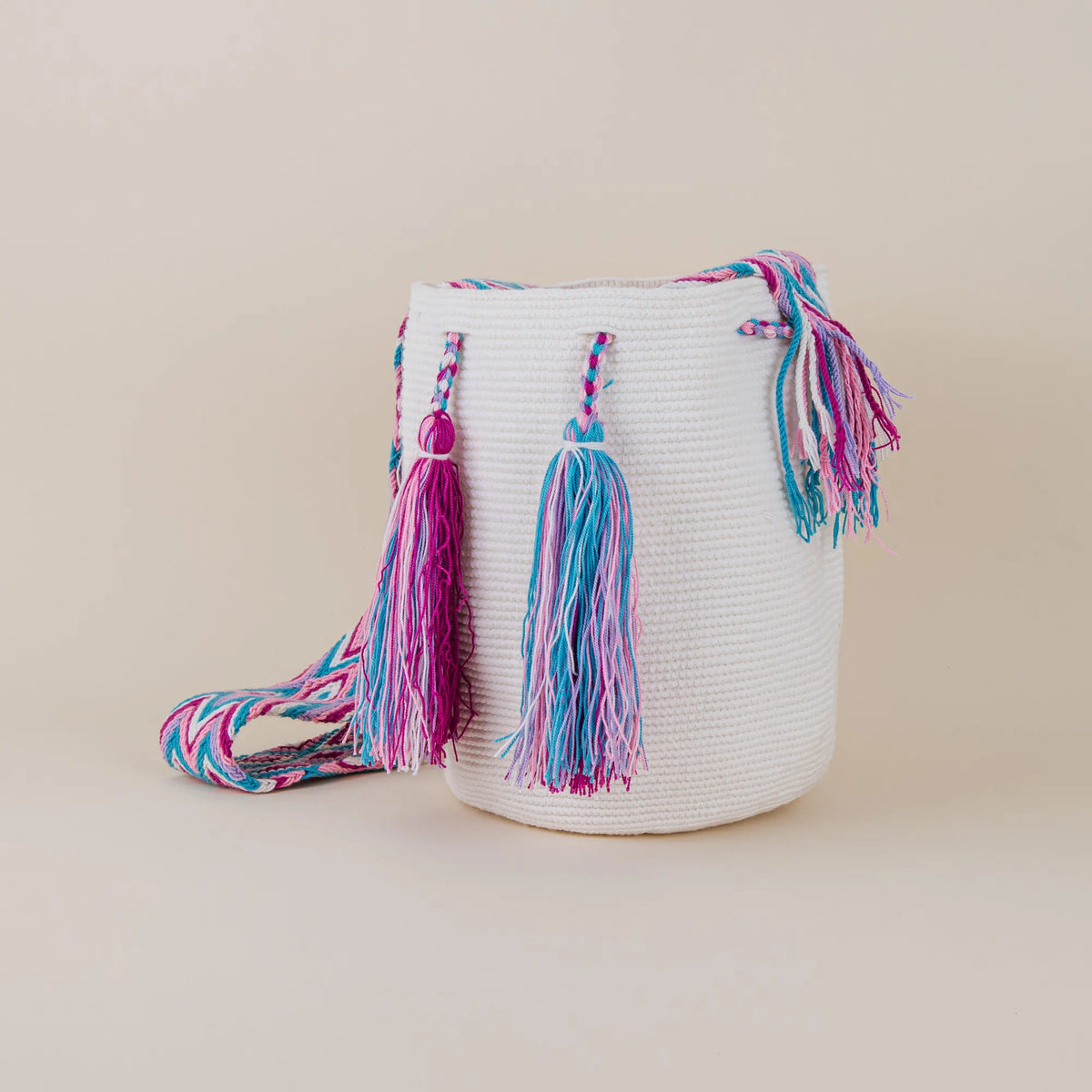 Angled view of Calera Wayuu Mochila featuring colorful pink, turquoise and purple tassels and handwoven strap – Maison Monserrate