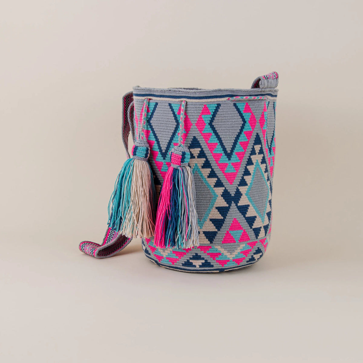 Angled view of Manati Wayuu Mochila showing intricate geometric patterns in pink, turquoise, navy and grey – Maison Monserrate