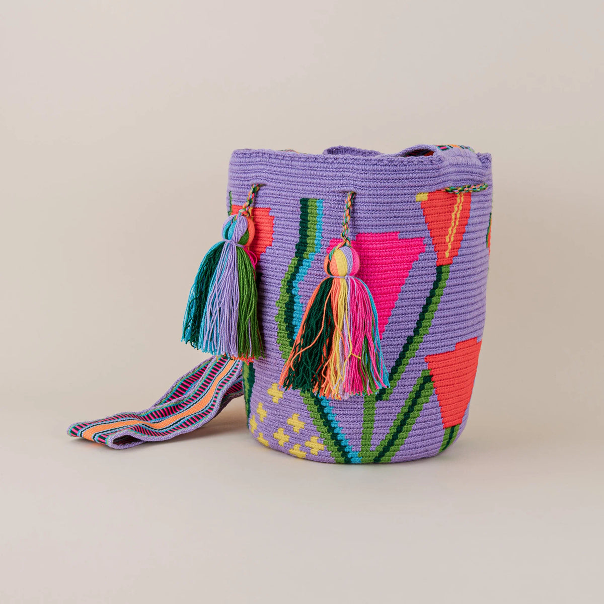 Angled view of Miraflores Wayuu Mochila featuring colorful floral weaving, multicolor tassels and patterned shoulder strap – Maison Monserrate