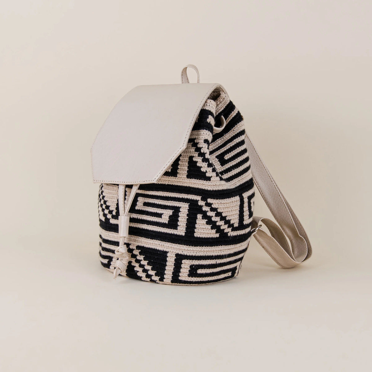 Angled view of Tolú Wayuu Backpack showing black and cream handwoven geometric pattern, cream flap and adjustable shoulder straps – Maison Monserrate