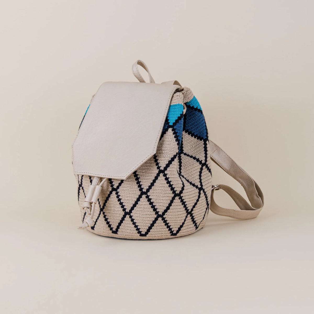 Angled side view of Coveñas Wayuu Backpack showing handwoven geometric pattern, cream flap and adjustable shoulder straps – Maison Monserrate