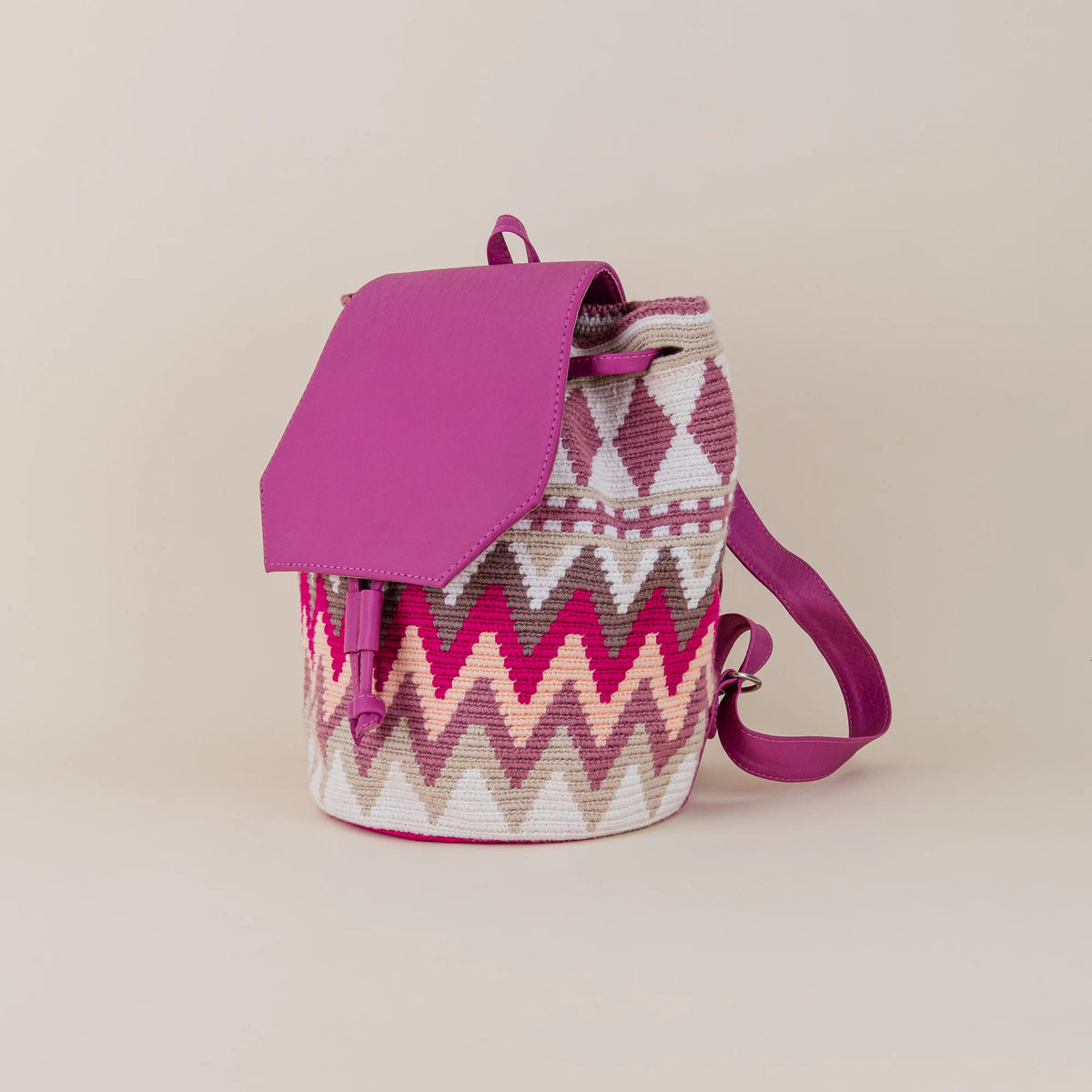 Angled view of Mompox Wayuu Backpack showing pink and cream handwoven geometric pattern, fuchsia flap and shoulder straps – Maison Monserrate