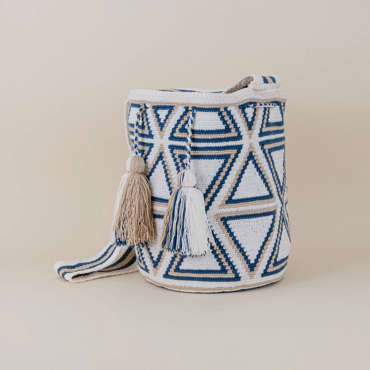 Angled view of Monteria Wayuu Mochila featuring navy blue, ivory and beige geometric patterns with handcrafted tassels – Maison Monserrate
